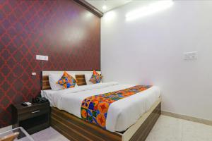 1 dormitorio con cama y pared roja en FabExpress SS Grand en Banthra Sikandarpur