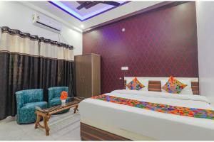 a bedroom with a bed and two blue chairs at FabExpress SS Grand in Banthra Sikandarpur