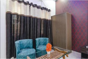 Habitación con 2 sillas azules y cortina en FabExpress SS Grand en Banthra Sikandarpur