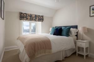 a white bedroom with a bed and a window at Charming 17th Century Cotswold Cottage in Adlestrop