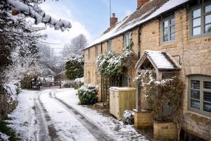 una calle cubierta de nieve frente a una casa en Charming 17th Century Cotswold Cottage, en Adlestrop