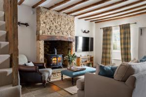 a living room with a fireplace and a couch at Charming 17th Century Cotswold Cottage in Adlestrop