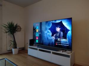 a flat screen tv sitting on a stand in a living room at Parc EXPO prte d'orléans ORLY CDG Terrasse parking in Bagneux