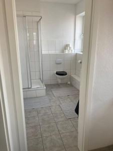 a white bathroom with a toilet and a shower at Rooftop mit Fördeblick, zentral & nah am HBF in Kiel +2 photos