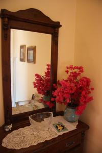 uno specchio sopra un comò con fiori rossi di Agriturismo San Leonardello a San Leonardello