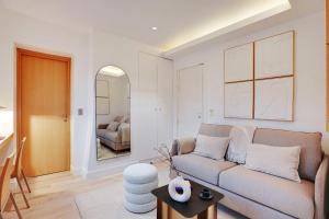 Chic Parisian Getaway 4P1BR - Victor Hugo في باريس: غرفة معيشة مع أريكة ومرآة