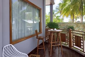 een balkon met een tafel en stoelen en een raam bij Watuduya Resort by The Lavana in Pasarbaru