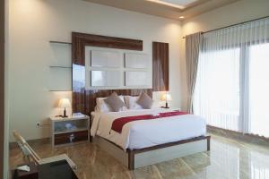 a bedroom with a large bed and a window at Watuduya Resort by The Lavana in Pasarbaru