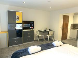 a bedroom with a bed and a table and a television at NelsonStays Self-Contained Studios Stoke on Trent in Stoke on Trent