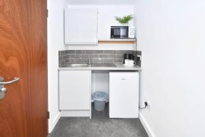 een kleine keuken met een wastafel en een magnetron bij NelsonStays Self-Contained Studios Stoke on Trent in Stoke on Trent