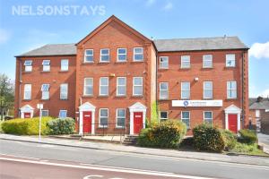 un gran edificio de ladrillo con puertas rojas en una calle en NelsonStays Self-Contained Studios Stoke on Trent en Stoke on Trent