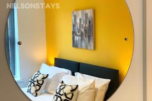 a mirror above a bed with white pillows at NelsonStays Self-Contained Studios Stoke on Trent in Stoke on Trent