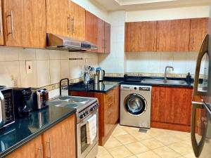 a kitchen with wooden cabinets and a washing machine at White Sage - Lakefront Apartment Amidst Parks With Lake Access in Dubai