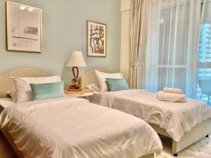 two beds in a room with a window at White Sage - Lakefront Apartment Amidst Parks With Lake Access in Dubai