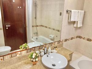 a bathroom with a sink and a toilet and a tub at White Sage - Lakefront Apartment Amidst Parks With Lake Access in Dubai
