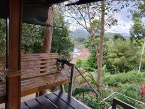 a bench on a porch with a view of a river at ภูริรักษ์ โฮมสเตย์ in Ban Pha Saeng Lang