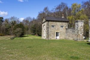 an old stone house in a field of grass at Leconfield Lodge in Petworth