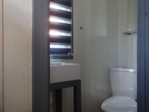 a bathroom with a sink and a toilet and a window at Shepherds Hut, Jamies Retreat, Bowness-on-Solway in Bowness-on-Solway