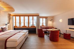 a hotel room with a large bed and a living room at Sonne Andermatt Swiss Quality Hotel in Andermatt