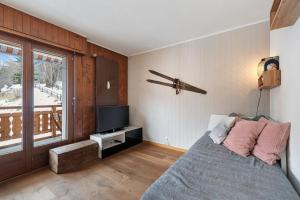 a bedroom with a bed and a tv and a window at Appartement chaleureux à Ovronnaz in Ovronnaz