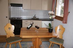 eine Küche mit einem Holztisch mit zwei Gläsern Wein in der Unterkunft Pra d'Sura 104 in Maloja