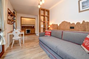 a living room with a couch and a kitchen at Residence Rta La Rosa delle Dolomiti in Carisolo