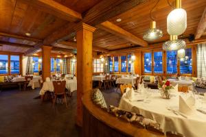a restaurant with white tables and chairs and windows at Sonne Andermatt Swiss Quality Hotel in Andermatt
