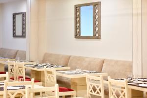 a dining room with tables and chairs and a couch at Santa Eulalia Hotel & Spa in Albufeira