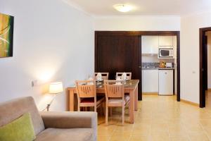 a living room with a dining room table and a kitchen at Santa Eulalia Hotel & Spa in Albufeira