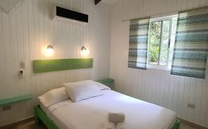 1 dormitorio con cama blanca y ventana en Boho lodge Montezuma l&l, en Montezuma