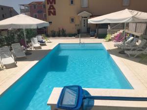 a large blue swimming pool with chairs and umbrellas at Apartments & Rooms Laganini in Zaton