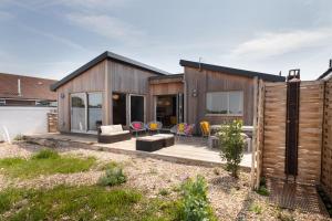 a wooden house with a deck and chairs at Sea Breezes in Pagham