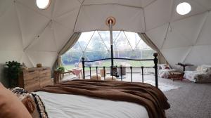 ein Schlafzimmer mit einem Bett in einem Zelt mit einem großen Fenster in der Unterkunft Luxury Dome with Private Wood-Fired Hot Tub in Oxford