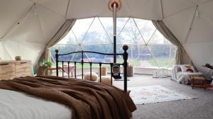 オックスフォードにあるLuxury Dome with Private Wood-Fired Hot Tubの大きな窓付きのテント内のベッド1台が備わるベッドルーム1室が備わります。