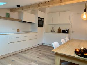 cocina con mesa de madera y armarios blancos en Haigis Lodge 2, en Annaberg im Lammertal