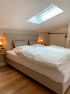a bedroom with a large white bed with a skylight at Haigis Lodge 2 in Annaberg im Lammertal