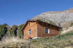 une petite maison en bois sur une colline avec une montagne dans l'établissement Almhütte Tauber Fane Alm, à Valles