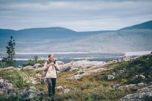 Una donna che cammina su una collina facendo una foto con una macchina fotografica di Lapland Hotels Äkäshotelli ad Äkäslompolo