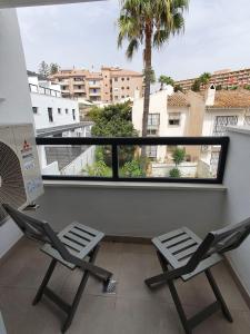 balkon z 2 krzesłami i dużym oknem w obiekcie Casa Torremolinos w mieście Torremolinos