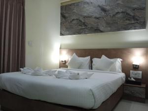 een slaapkamer met een groot wit bed en handdoeken bij Tranquil-Homes Ishwerya Suites in Bangalore