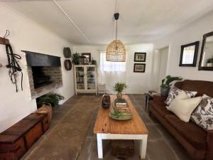 ein Wohnzimmer mit Tisch und Couch in der Unterkunft Cornellskop Country Stay in Botrivier