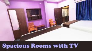 een slaapkamer met 2 bedden, 2 stoelen en paarse muren bij Hotel MG INN Kanipakam in Kanipakam
