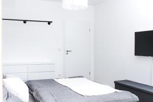 a white bedroom with a bed and a tv at Panorama Schwarzenberg in Schwarzenberg