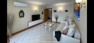 a living room with a white couch and a tv at Paradis Bleu in Albufeira