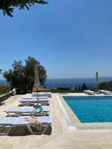 a row of lounge chairs next to a swimming pool at Assos Luna Houses in Ayvacık
