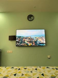 a tv hanging on a green wall with a clock at Studio Apt with Rooftop Panoramic views @ Dabolim in Vasco Da Gama