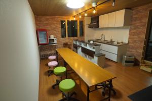 uma cozinha com uma mesa de madeira e cadeiras verdes em Guest House Ihatov - Vacation STAY 00941v em Takamatsu