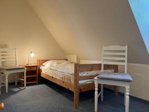 a bedroom with a bed and two chairs at Greggersen - Whg 2 in Nieblum