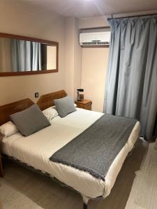 Un dormitorio con una cama grande y una ventana en Hostal Arenal, en Zaragoza