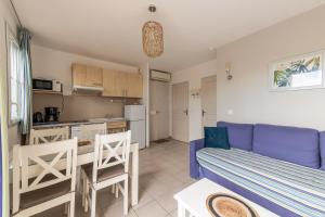 uma sala de estar com um sofá azul e uma cozinha em L'Arbois - T2 avec piscine entre Aix et Marseille em Cabriès